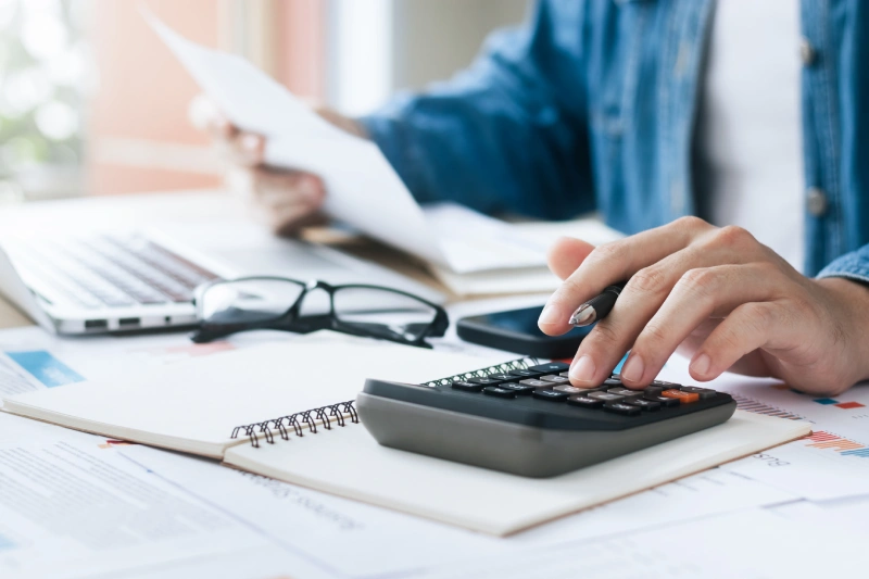 GettyImages-1437026399 Person using calculator at a desk.
